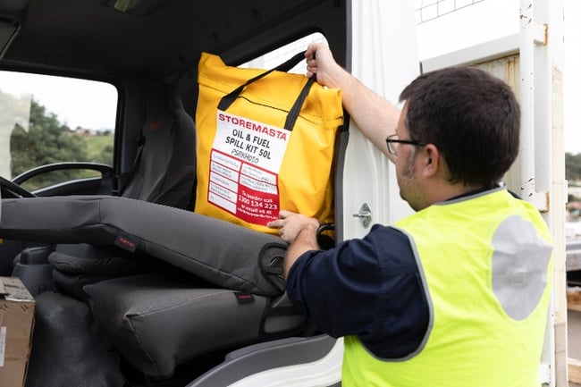 man placing a spill kit back in the cab of a vehicle