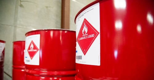 Flammable liquid handled in three red drums with diamond-shaped dangerous goods signages