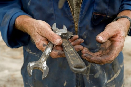 worker's hands holding dirty wrenches
