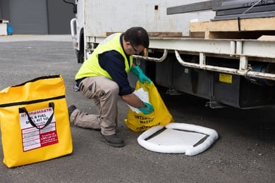 spill kit - worker putting wipes in waste bag 