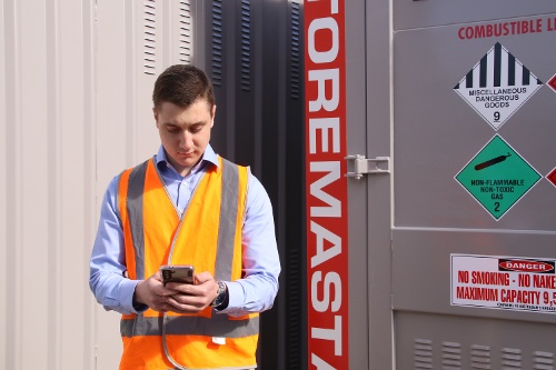 Braden looking at phone outside near container 56kb