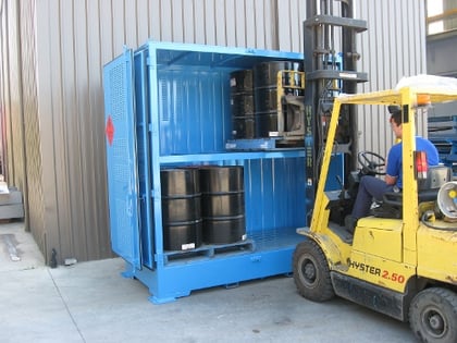worker loading drums into a container by forklift