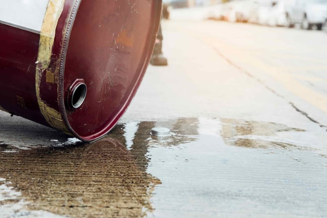 small chemical drum spilling liquid over concrete