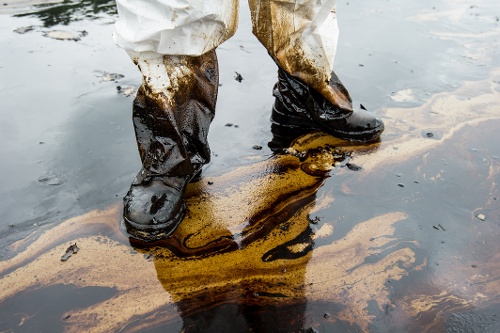 worker with protective boots standing in oil spill