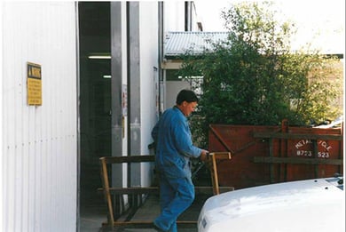 a worker moving a frame outside from the factory