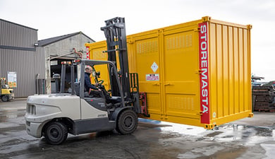 worker forklifting the yellow container outside of the factory